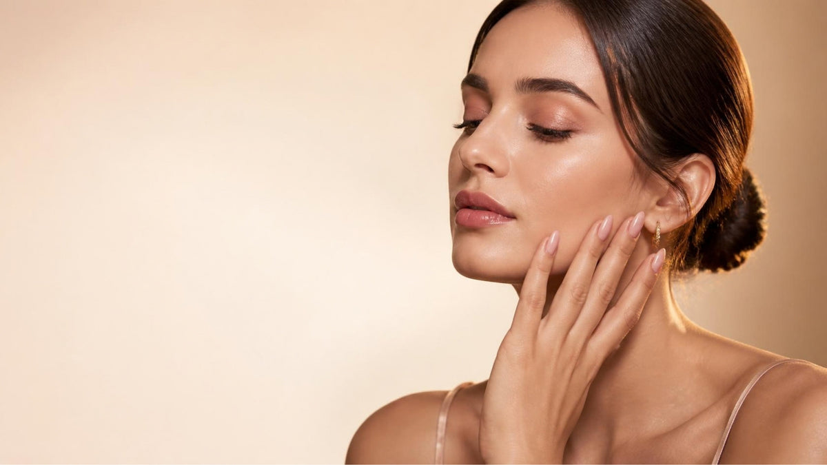 Femme élégante, main sur le visage, manucure nude rosé VAYRON